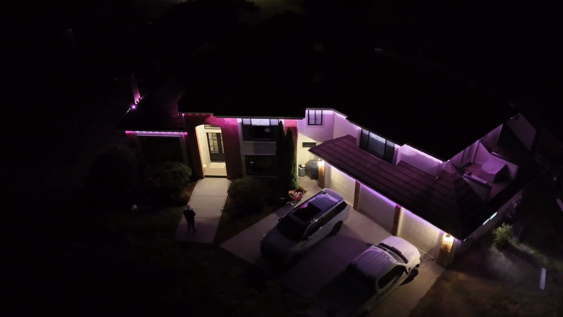 Drone view at night of a home with its rooflines outlined in purple lights, installed by Wonderboy